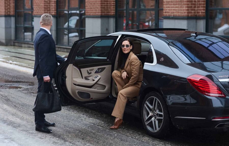 Chauffeur opening the rear door of an executive Mercedes